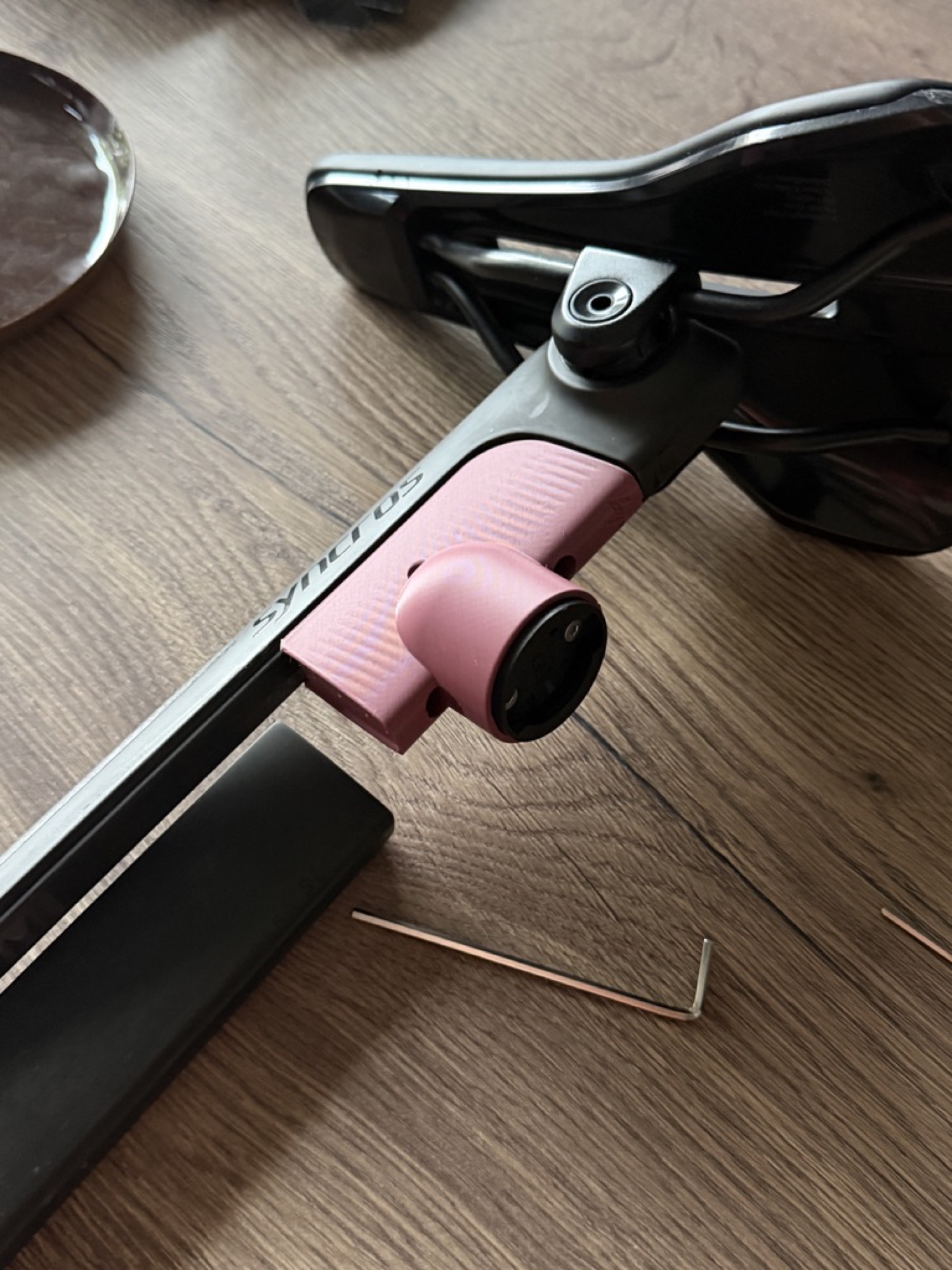A pink test print of the mount fitted to a Syncros seatpost on the bench